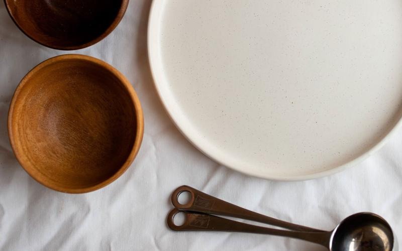 bowls, a plate and measuring spoons arranged neatly on cloth