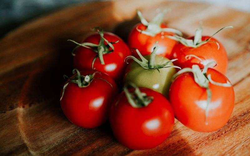 bunch of tomatoes on a wooden plate